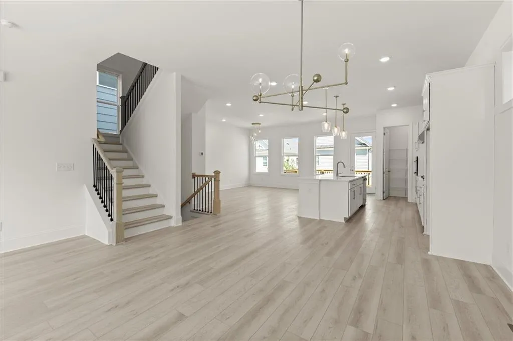 Kitchen featuring open floor plan, a sink, white cabinetry, pendant lighting, and light wood-style flooring