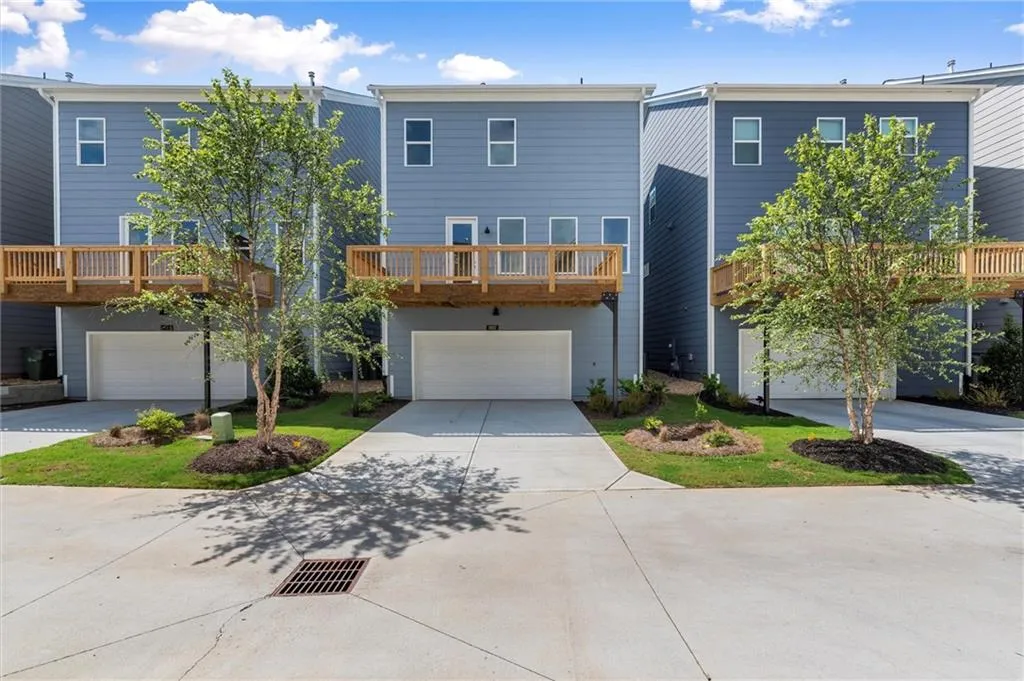 View of front of house featuring an attached garage, concrete driveway, and a balcony