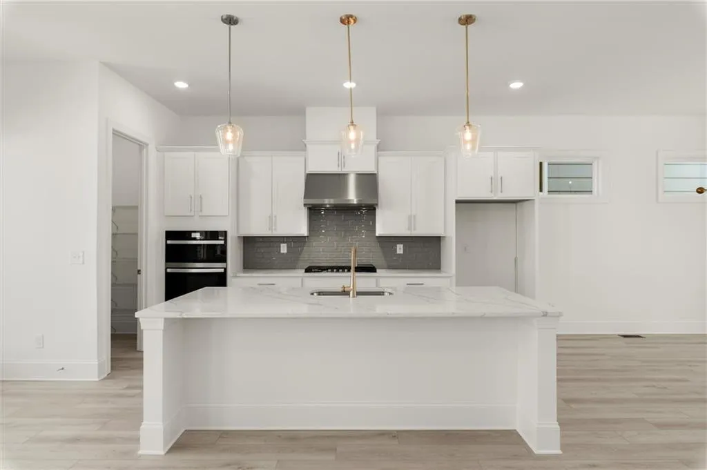 Kitchen featuring under cabinet range hood, black appliances, white cabinetry, baseboards, and decorative backsplash