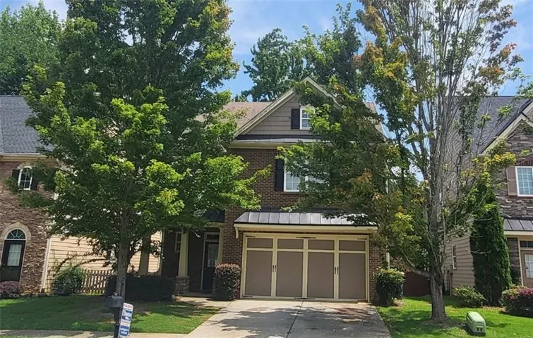 Traditional style residence featuring a brick facade, shingle roofing, and a two-car garage with decorative paneling