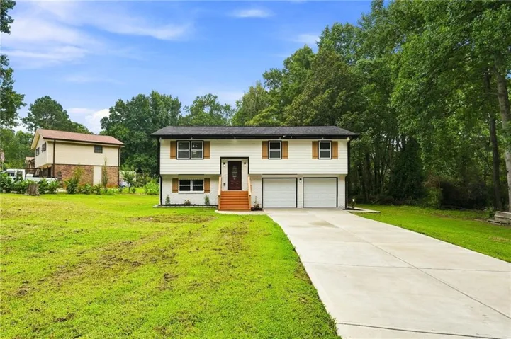 Split-level exterior with white siding, contrasting shutters, two-car garage, and concrete driveway