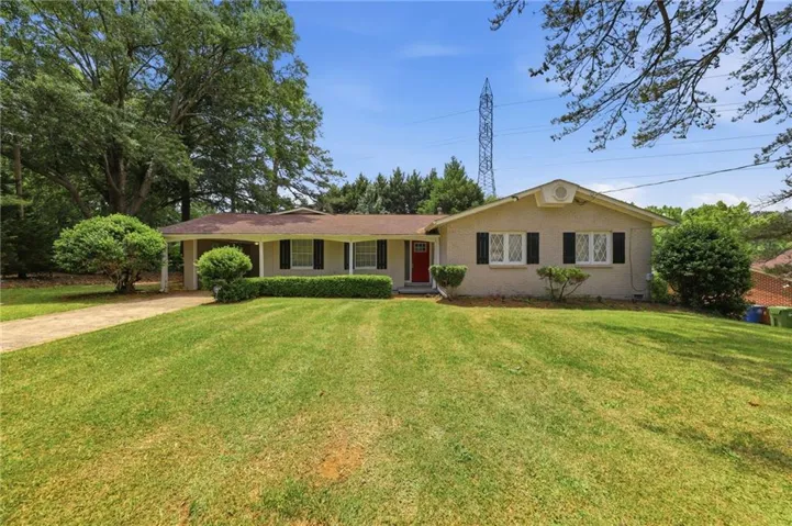 Ranch-style residence featuring a prominent front lawn, mature trees, and a covered entryway