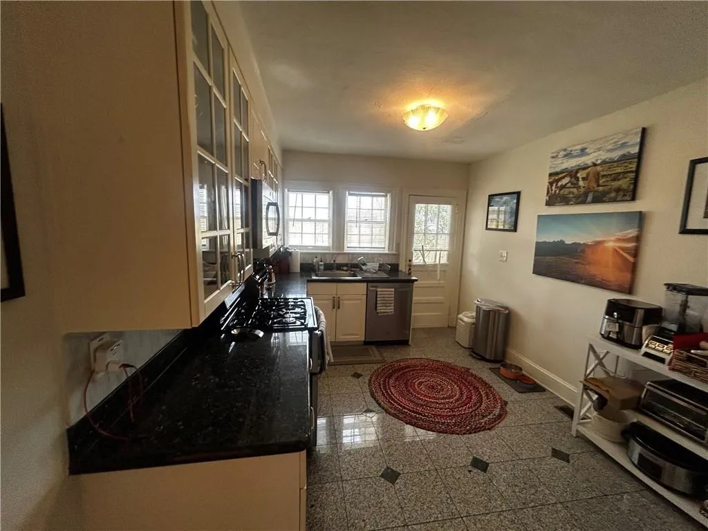 Kitchen with glass insert cabinets, granite floors, and appliances with stainless steel finishes