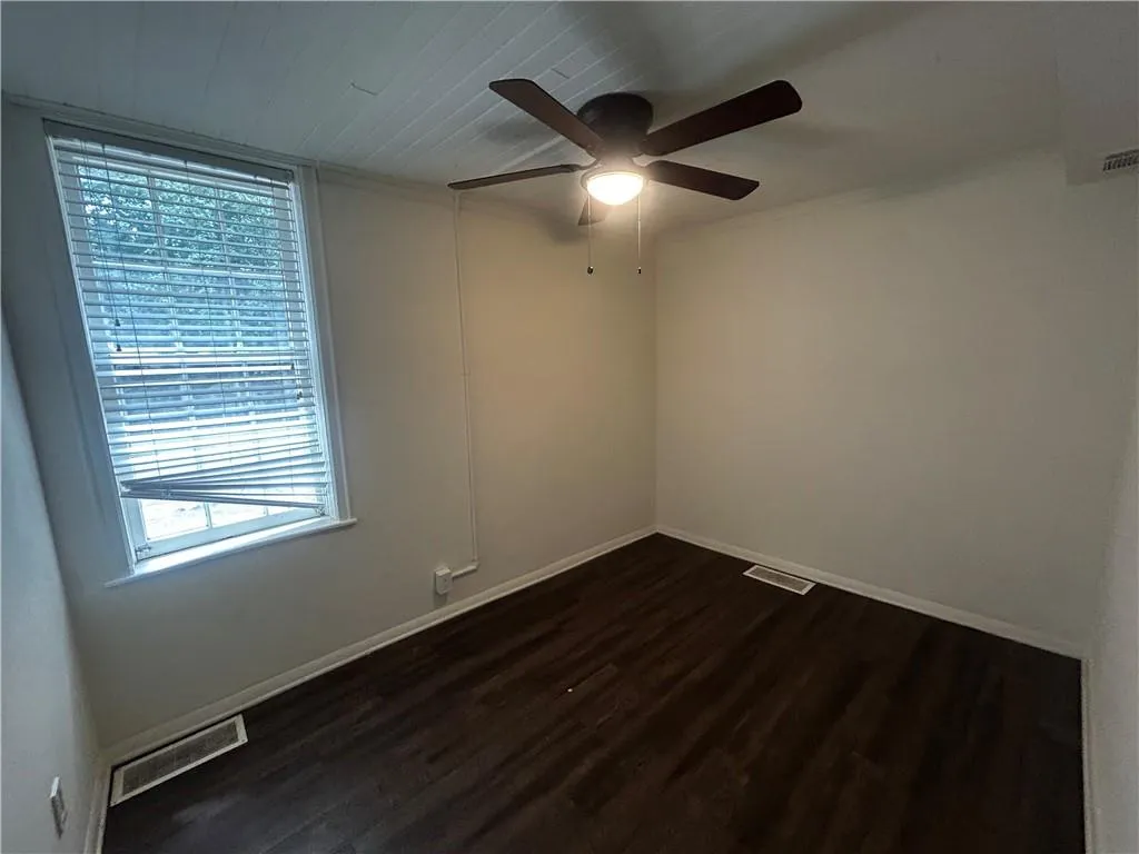 Empty room featuring dark wood-style floors and ceiling fan