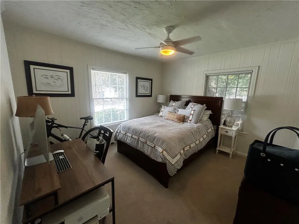 Bedroom featuring a textured ceiling, ceiling fan, carpet, ornamental molding, and wooden walls