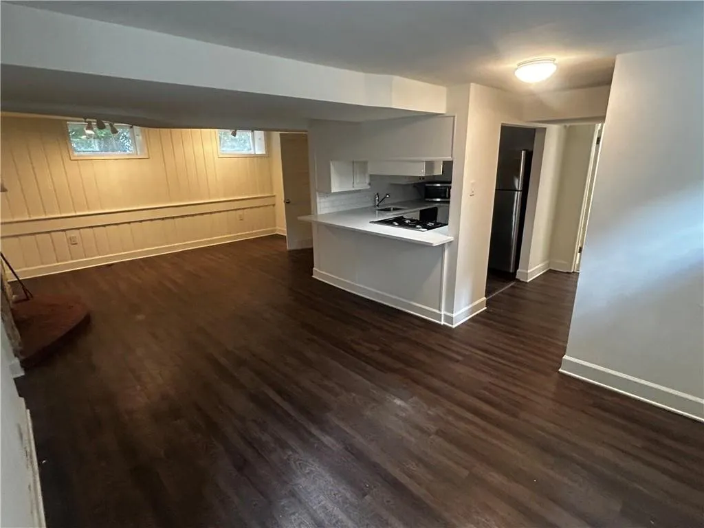 Kitchen featuring dark wood-type flooring, light countertops, freestanding refrigerator, open floor plan, and a peninsula