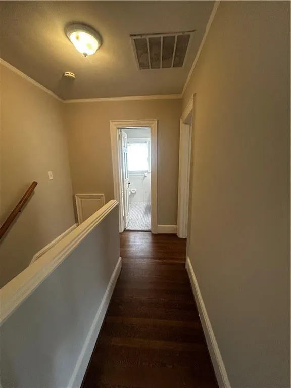 Hall featuring dark wood-type flooring, an upstairs landing, and crown molding