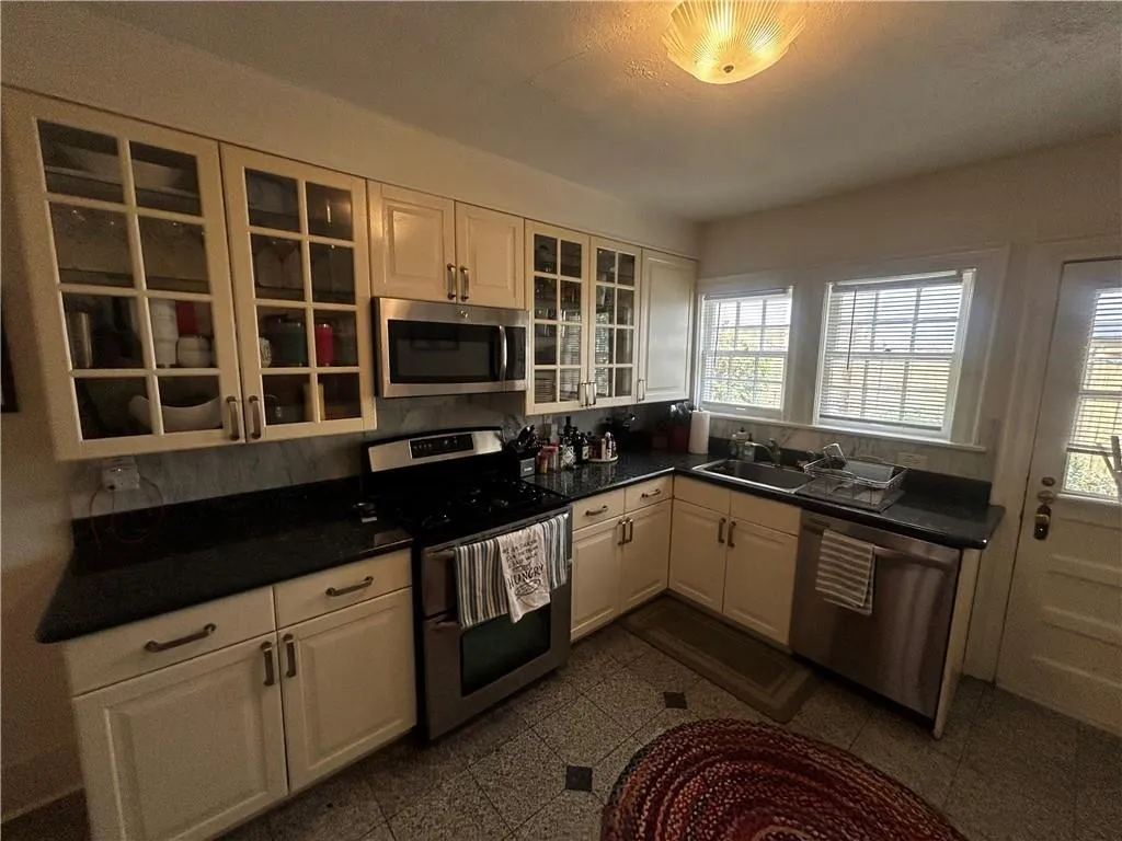 Kitchen with stainless steel appliances, white cabinetry, and glass insert cabinets