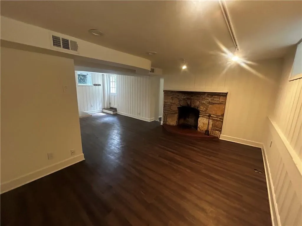 Unfurnished living room featuring dark wood-type flooring and a fireplace