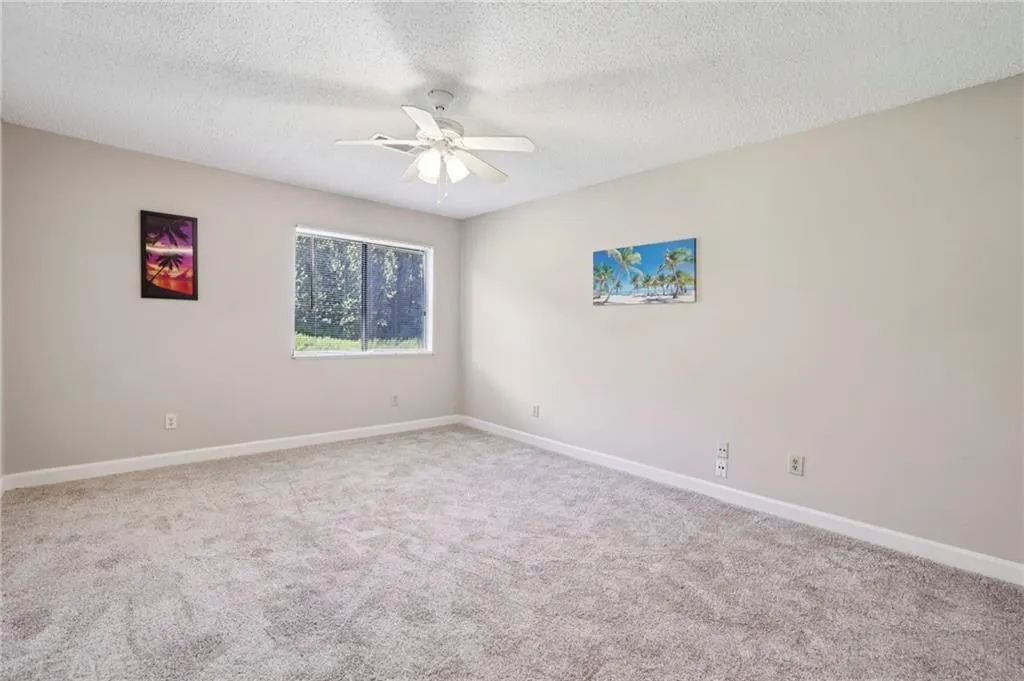 Empty room with a textured ceiling, carpet, and ceiling fan