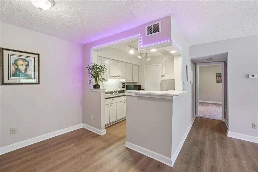 Kitchen with white cabinetry, a textured ceiling, light wood-style floors, an open bar and LED lighting