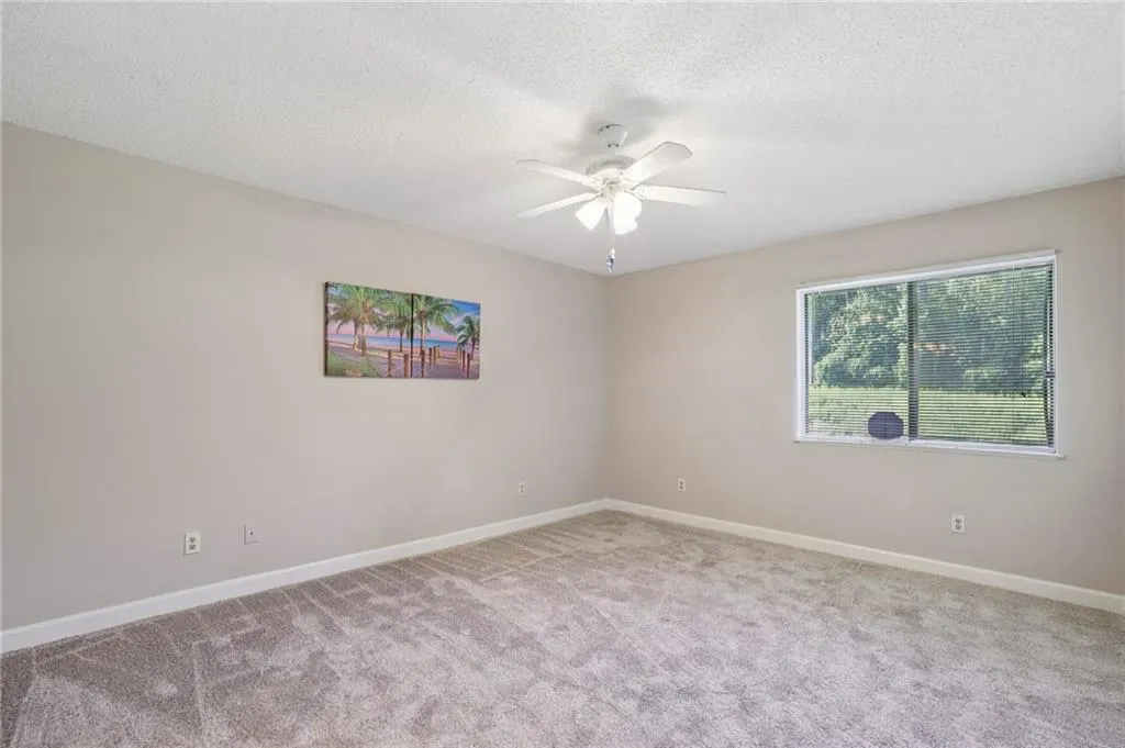 Bedroom featuring light carpet, a textured ceiling, and a ceiling fan