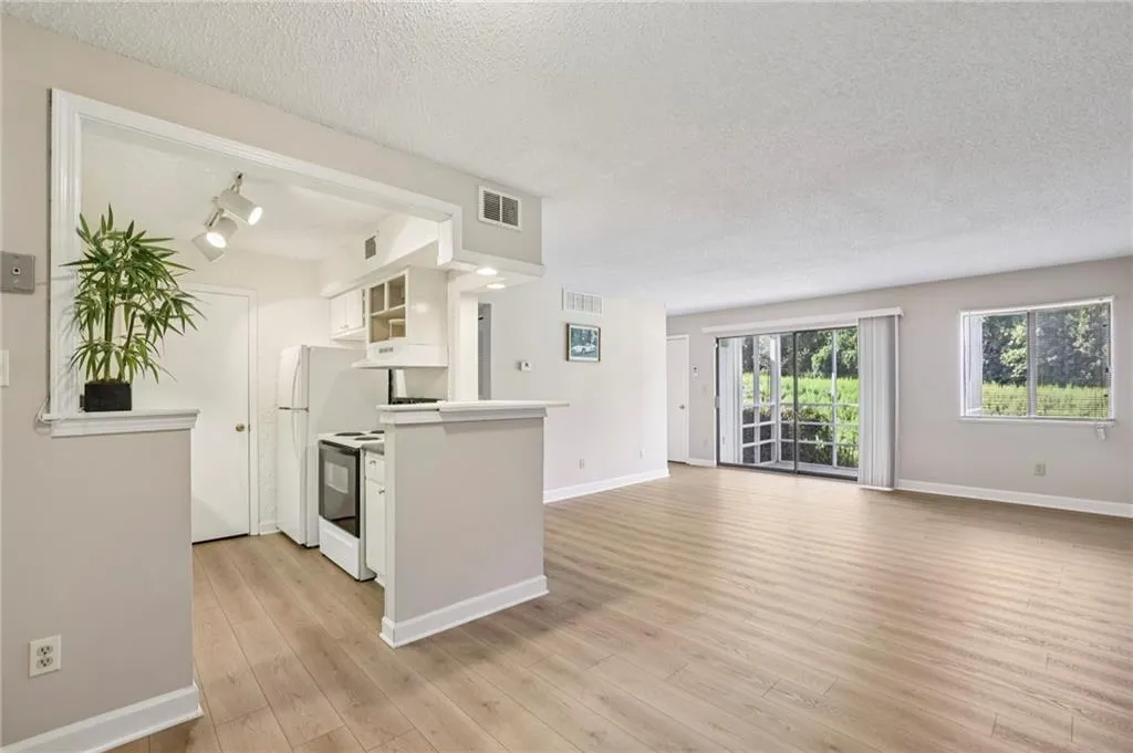 Kitchen with white cabinetry, a textured ceiling, open floor plan, rail lighting, and glass insert cabinets