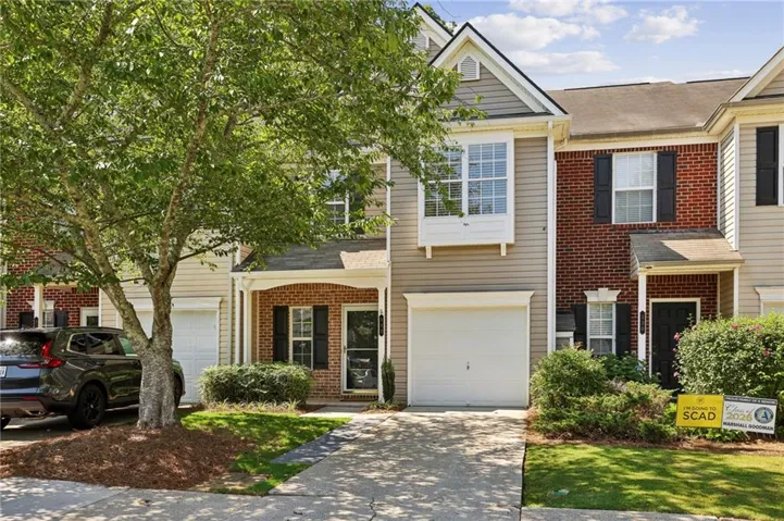 Multi-story townhome featuring a mix of brick and siding, a covered front entry, a single-car garage, and a bay window