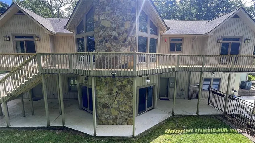 Multi-level exterior with a stone-clad chimney and a full-width upper deck
