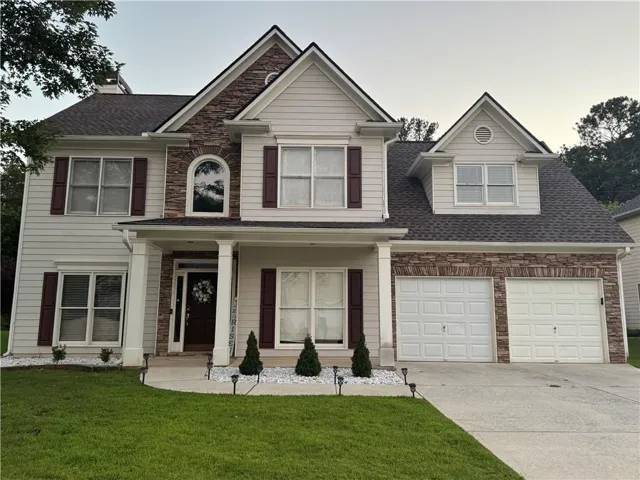 Two-story residence featuring light-colored siding and stone veneer accents