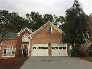 Multi-level residence featuring brick and horizontal siding, a two-car garage, and an arched entry with a transom window