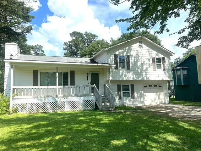 Split-level residence featuring white siding, a covered front porch with white railings, and an integrated garage