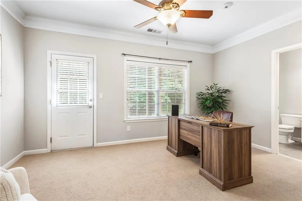 Office space/Guest Bedroom and Bath with light carpet, a ceiling fan, and ornamental molding
