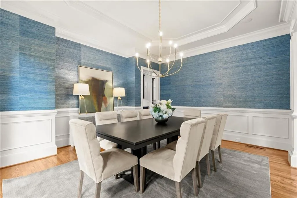 Dining area featuring wallpapered walls, hanging lights, crown molding, a wainscoted wall, and a decorative wall