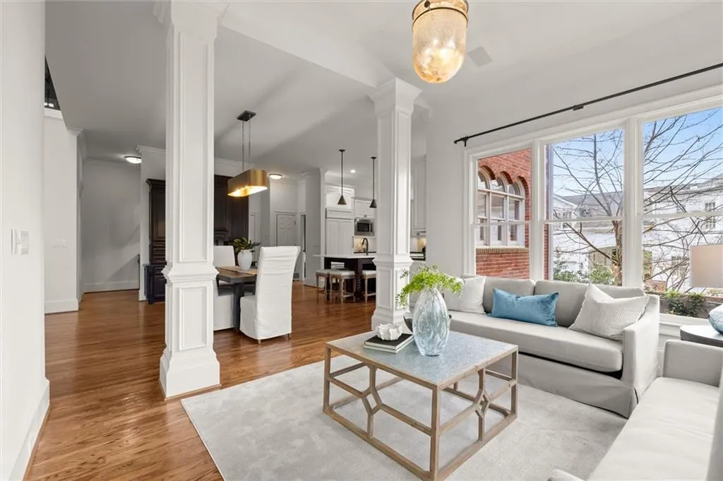 Living room with decorative columns, wood finished floors, and crown molding