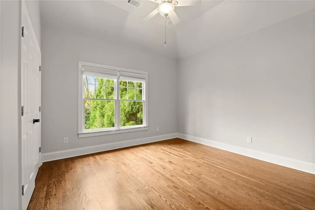 Unfurnished room featuring light wood-type flooring, a ceiling fan, and lofted ceiling