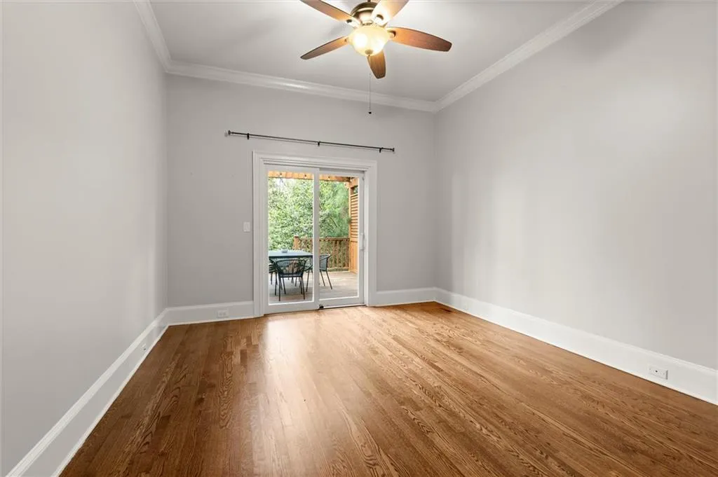 Unfurnished room featuring wood finished floors, ornamental molding, and a ceiling fan
