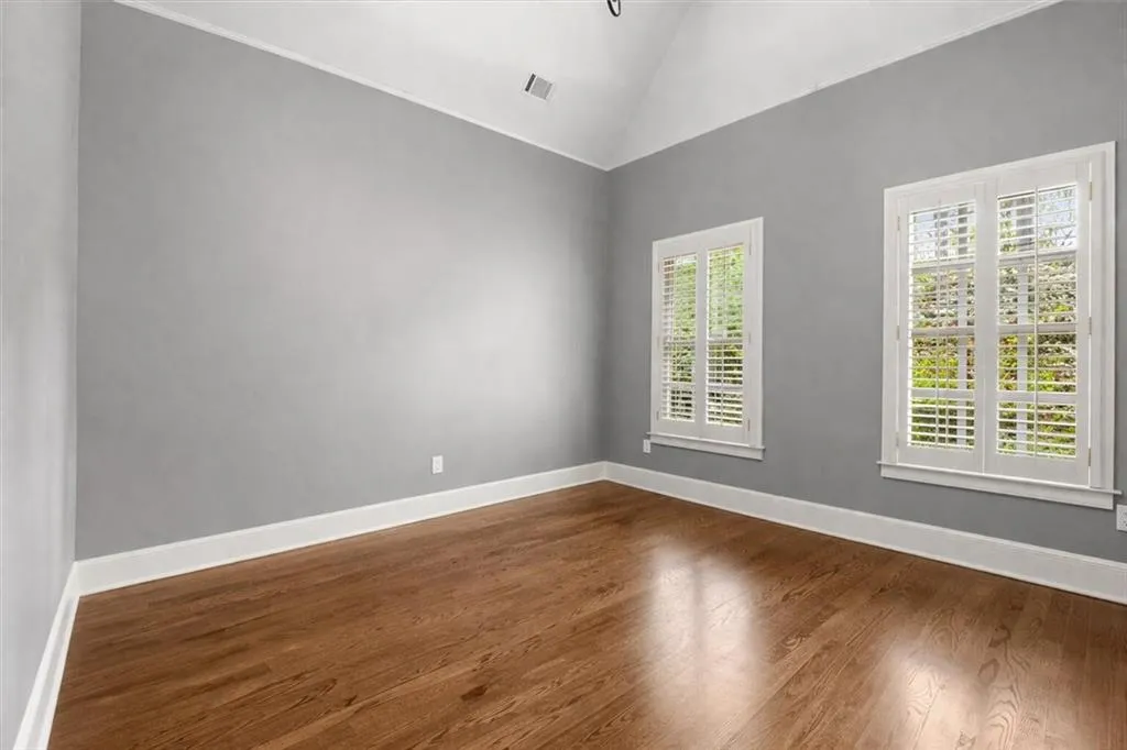 Unfurnished room featuring lofted ceiling and dark wood-style flooring