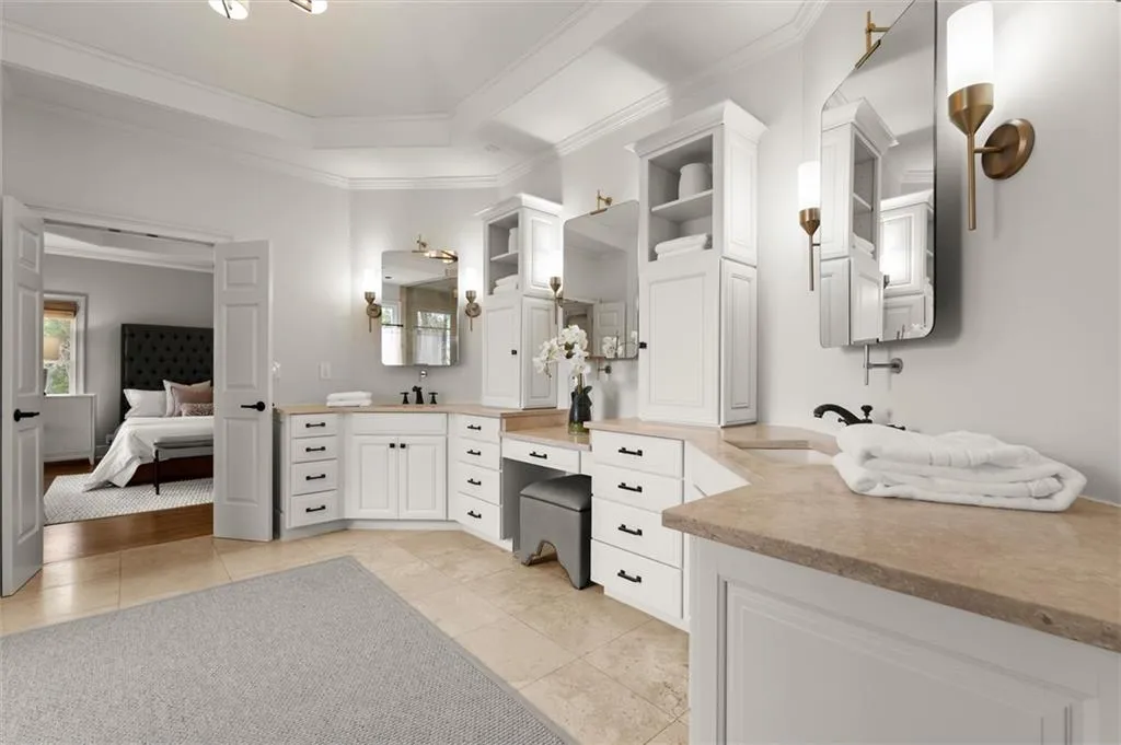 Full bathroom featuring two vanities, ensuite bath, ornamental molding, light tile patterned floors, and a tray ceiling