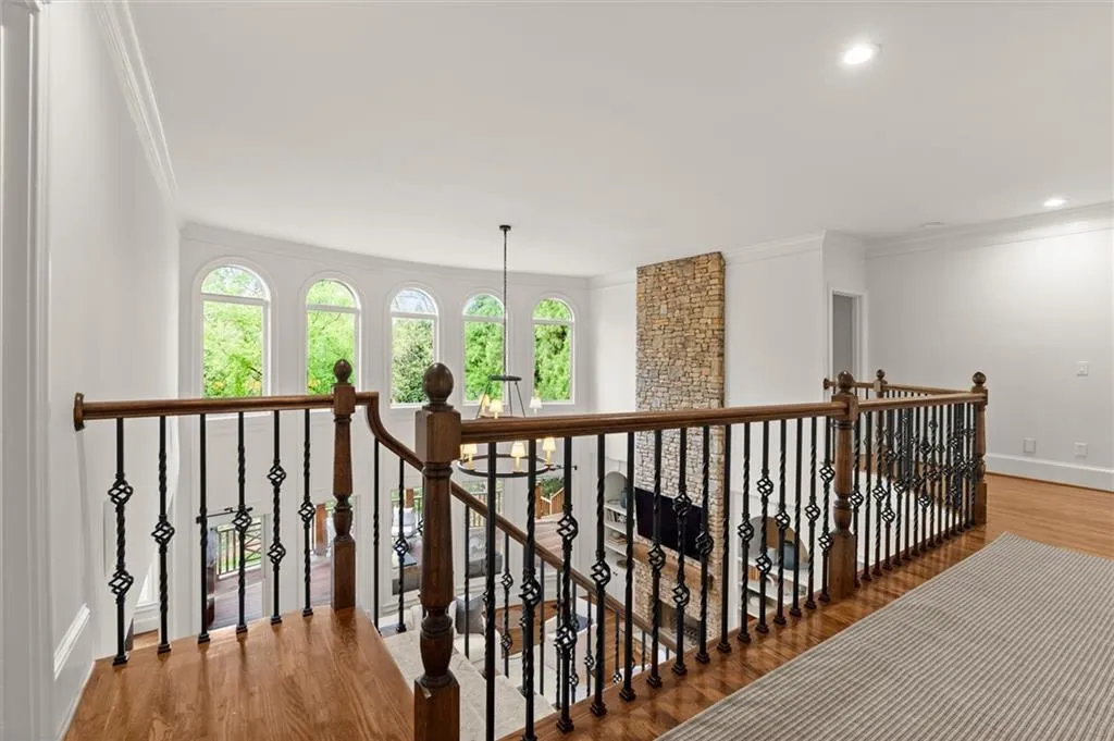 Hallway with light wood-type flooring, ornamental molding, an upstairs landing, and recessed lighting