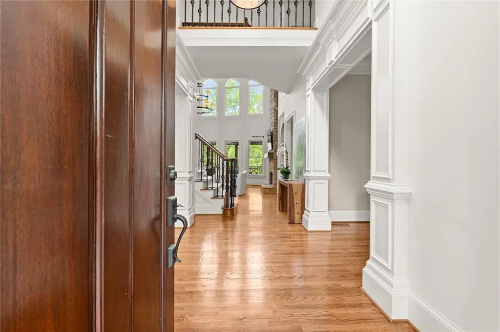 Entryway featuring light wood-style flooring, a high ceiling, ornamental molding, and arched walkways