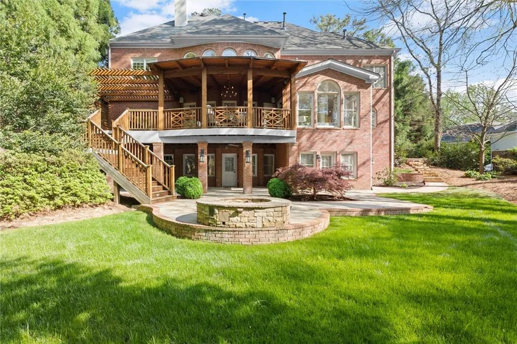 Rear view of house with a patio, brick siding, a balcony, and a yard