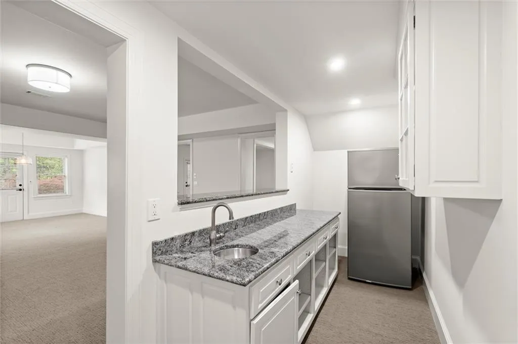 Kitchen with light carpet, dark stone counters, white cabinetry, freestanding refrigerator, and recessed lighting