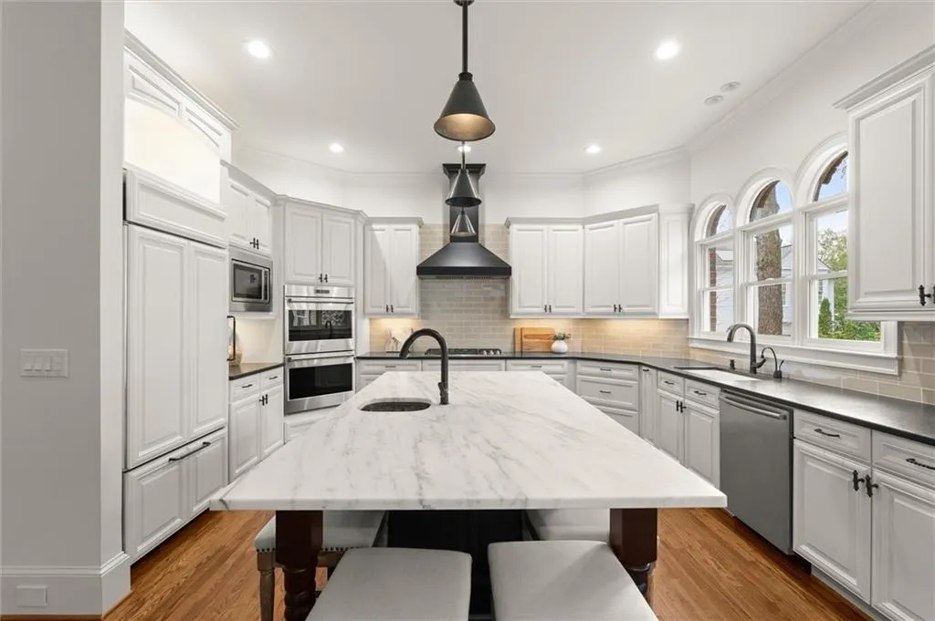 Kitchen featuring a breakfast bar, light wood-type flooring, white cabinetry, built in appliances, and ornamental molding