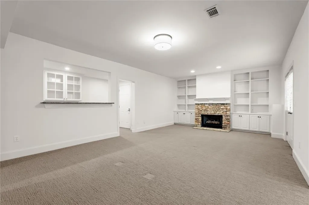 Unfurnished living room featuring carpet floors, a fireplace, built in shelves, and recessed lighting