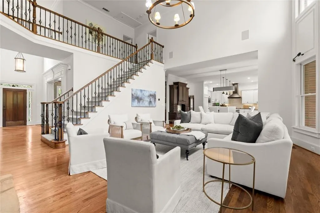 Living room featuring suspended lighting, wood finished floors, a high ceiling, and crown molding