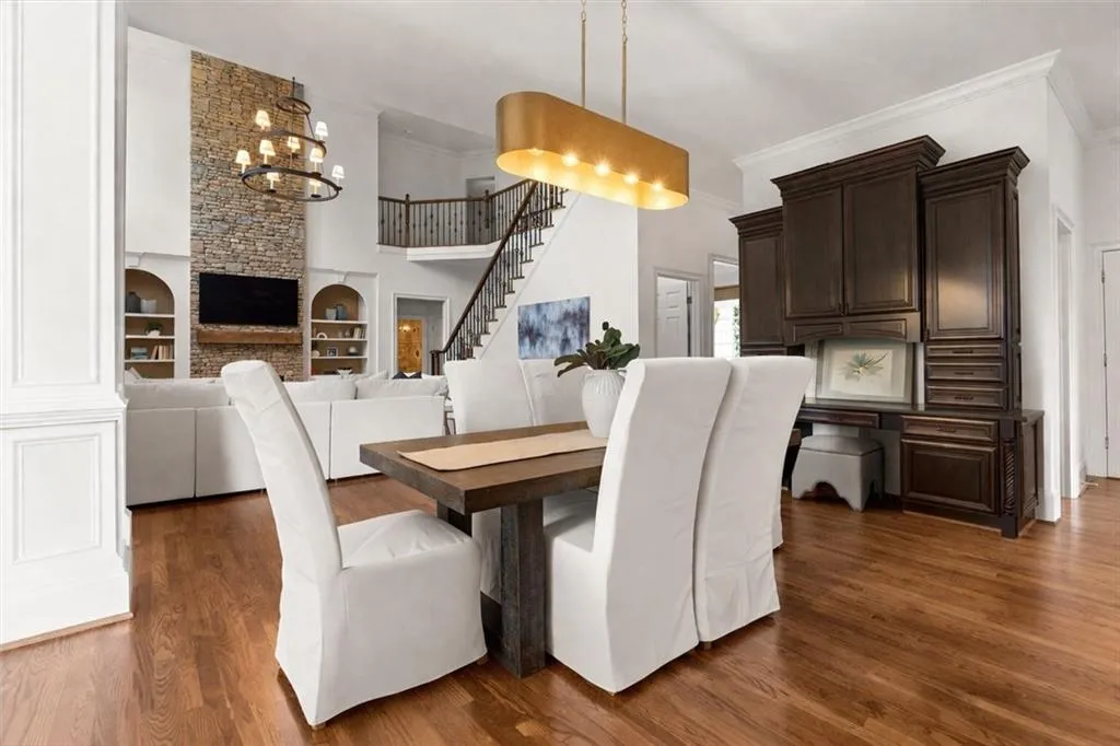 Dining space featuring crown molding, a fireplace, dark wood-style flooring, and suspended lighting