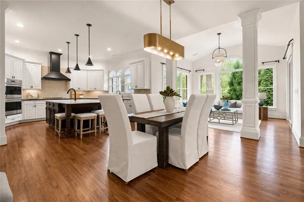 Dining space featuring dark wood-style floors, decorative columns, hanging lights, and lofted ceiling
