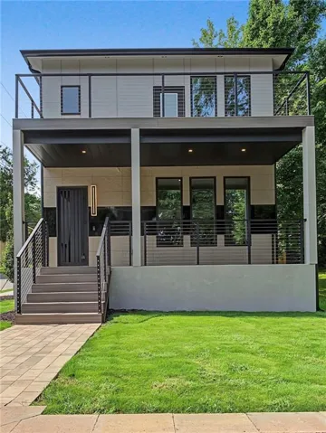 Modern multi-level residence featuring a flat roof and a full-width upper-level balcony with cable railings