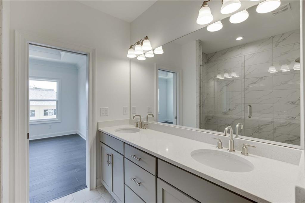 The primary bath view with grey cabinetry and double vanities.