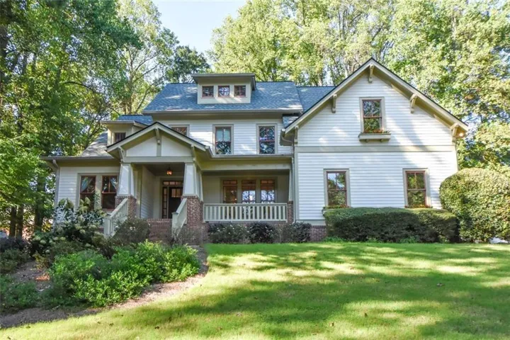 Craftsman-style exterior with a covered front porch, brick column bases, light-colored siding, and multiple dormer windows