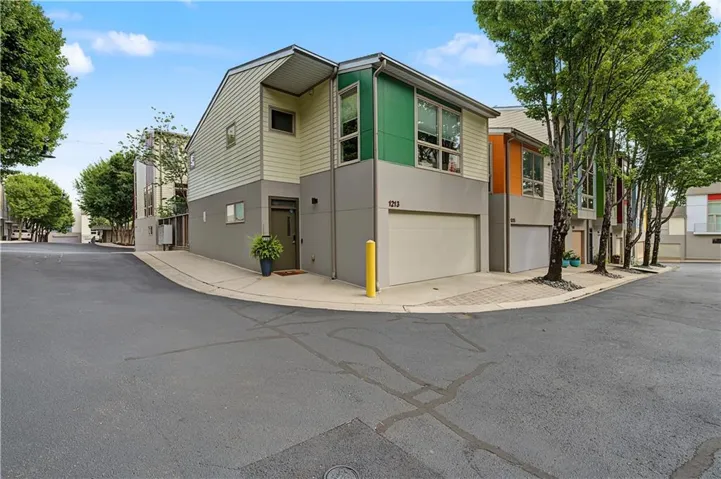 Contemporary multi-story exterior featuring vibrant green and neutral-toned siding, integrated garage, and a covered entryway