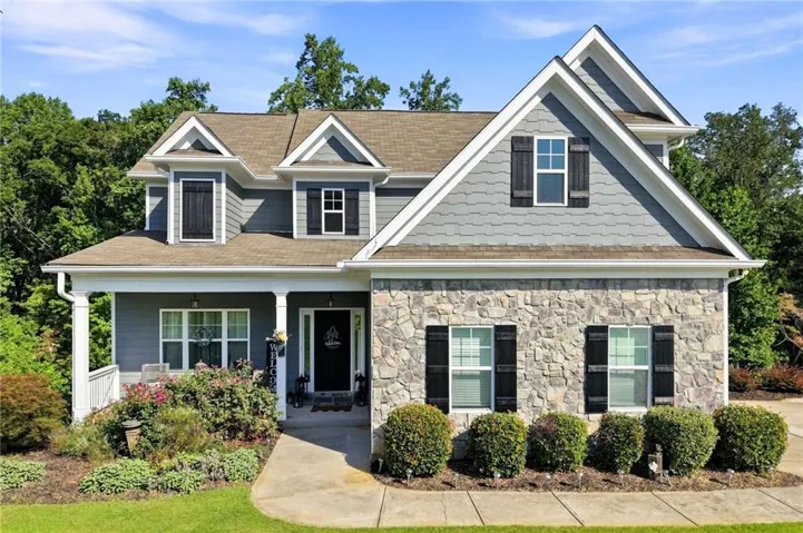 Stone and siding exterior with dark shutters, covered front porch, and dormer windows