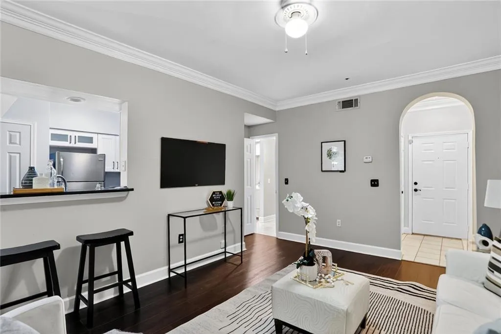 Living area with ornamental molding, wood finished floors, and arched walkways