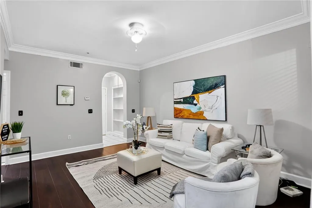 Living area with arched walkways, ornamental molding, and wood finished floors