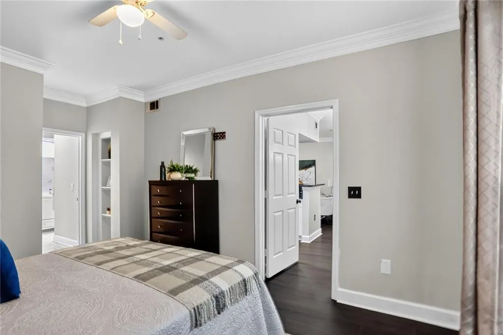 Bedroom with ornamental molding, dark wood finished floors, and connected bathroom