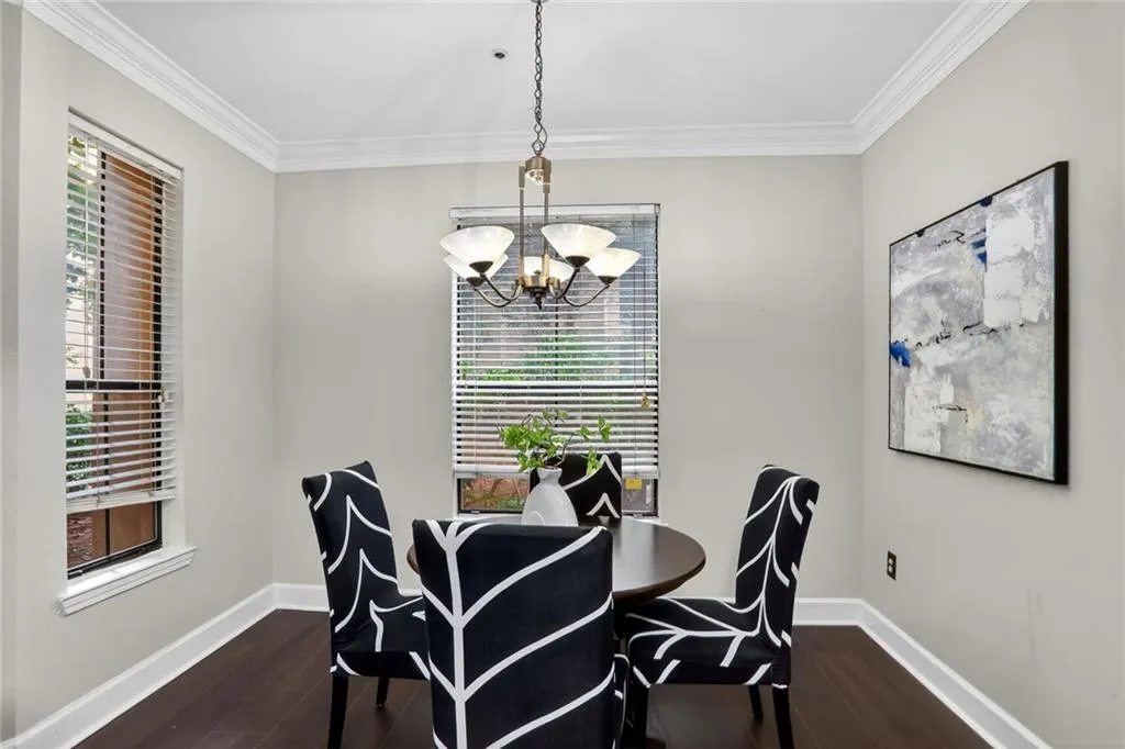 Dining room featuring ornamental molding, a chandelier, and dark wood finished floors
