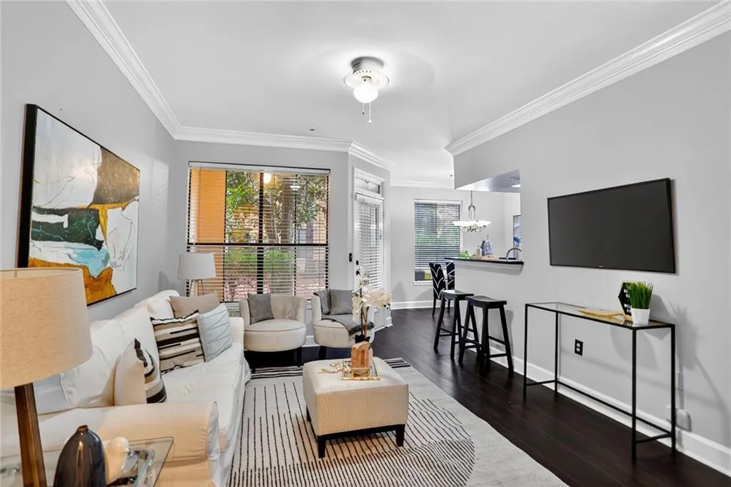 Living room with ornamental molding, a chandelier, wood finished floors, and a ceiling fan
