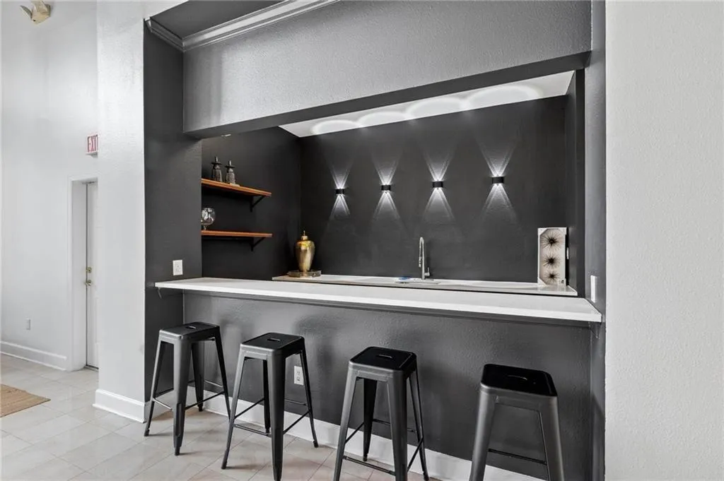Indoor wet bar with a textured wall and baseboards