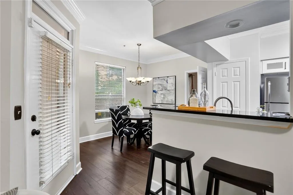 Kitchen with crown molding, a breakfast bar, dark wood finished floors, freestanding refrigerator, and decorative light fixtures